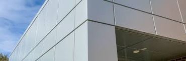 Modern building corner with sleek panel facade under blue sky.