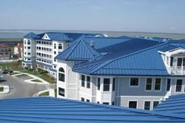 Coastal buildings with blue metal roofs under a clear sky.