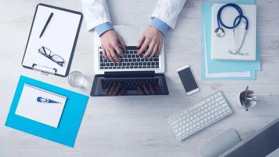 Open laptop next to stethoscope and patient documentation