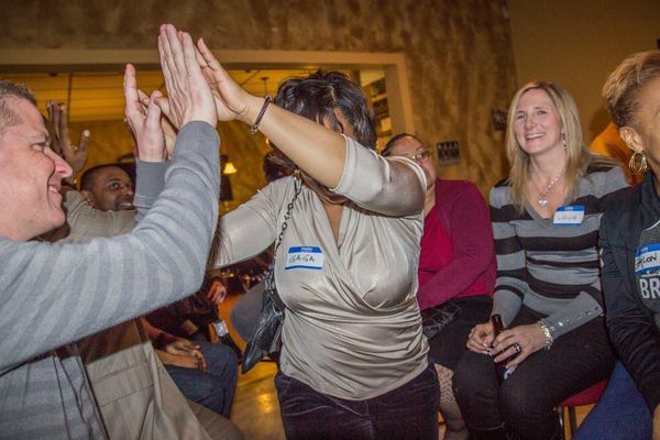 People joyfully high-fiving at a social gathering.