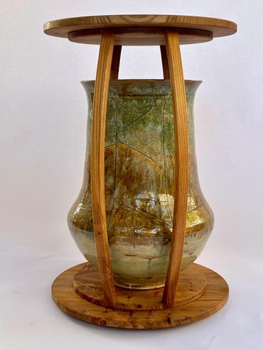 Wooden display stand holding a large ceramic vase.