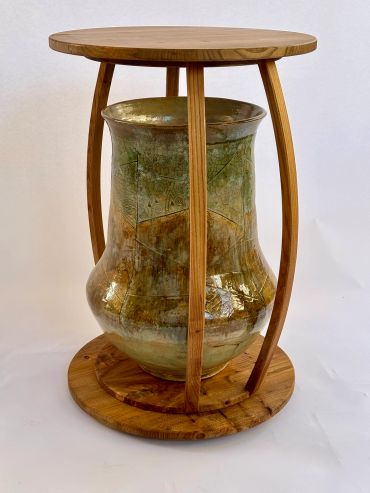 A rustic ceramic vase supported by a wooden frame.