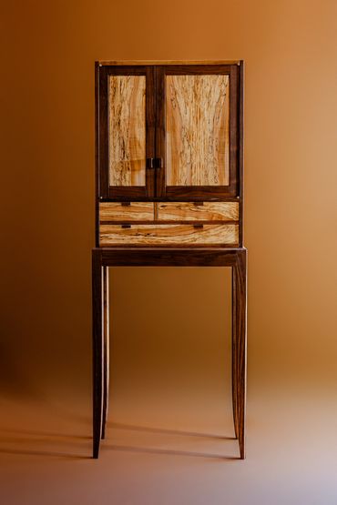 Wooden cabinet with drawers on tall legs.