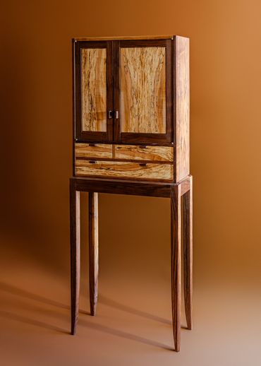 Elegant wooden cabinet with natural wood grain on tall legs.