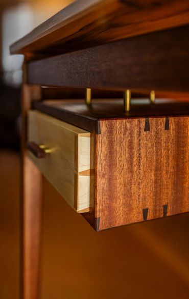 Close-up of a wooden drawer with dovetail joints and brass hardware.