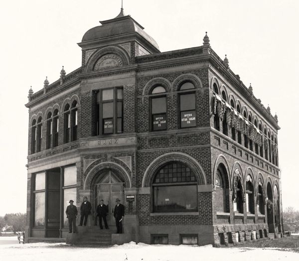 Historic brick bank building with four men standing at the entrance.