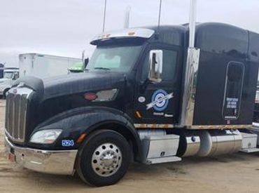 Black semi-truck parked in lot.