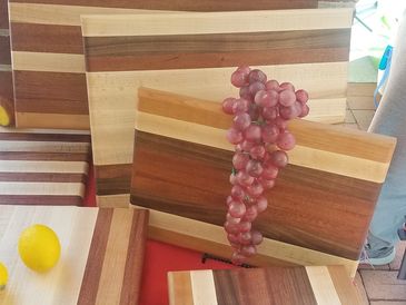 Stacked wooden cutting boards with a bunch of grapes on top.