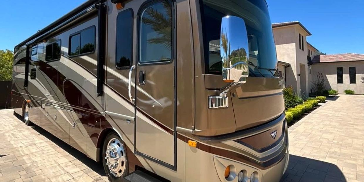 Luxury motorhome parked on a driveway in front of a modern house.