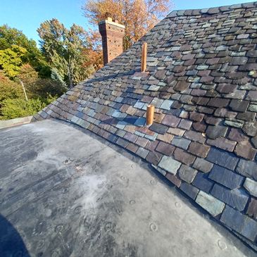 Custom copper pipe flashing, EPDM rubber flat roof, and slate roofing repairs and restoration.