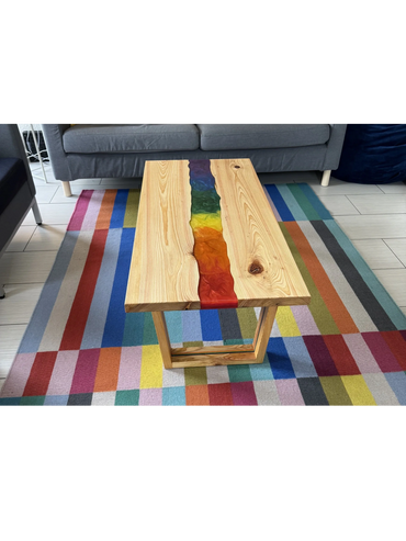 Wooden table with a vibrant rainbow resin inlay on a colorful checkered rug.