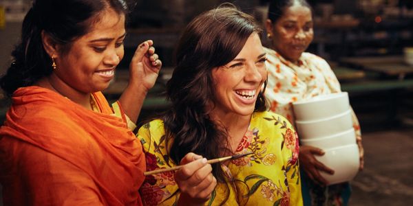 Three women happily engaged in pottery painting together.