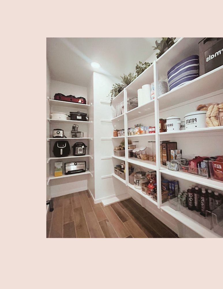 Organized pantry with shelves stocked with appliances, canned goods, and snacks.