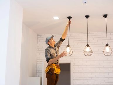 Electrician worker installation electric lamps light inside apartment.