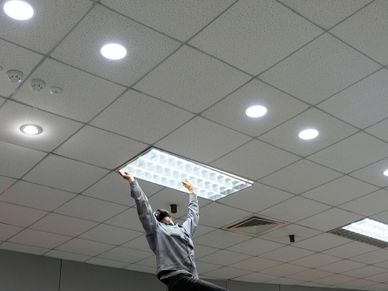 Maintenance man changing light bulbs in office