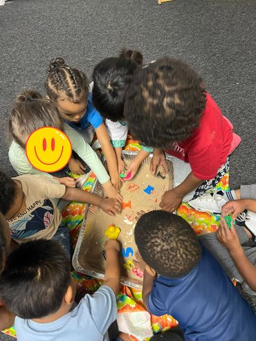 Children playing with letters in a sand tray together.