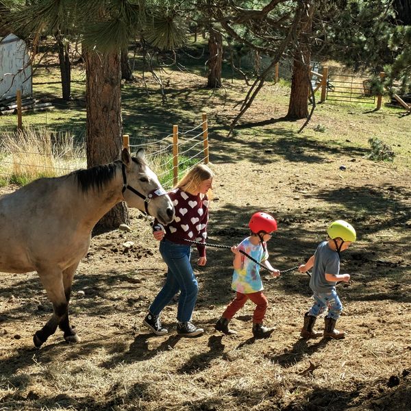 Woman and children leading a horse on a dirt path.