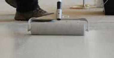 Person using a roller to paint a floor white.