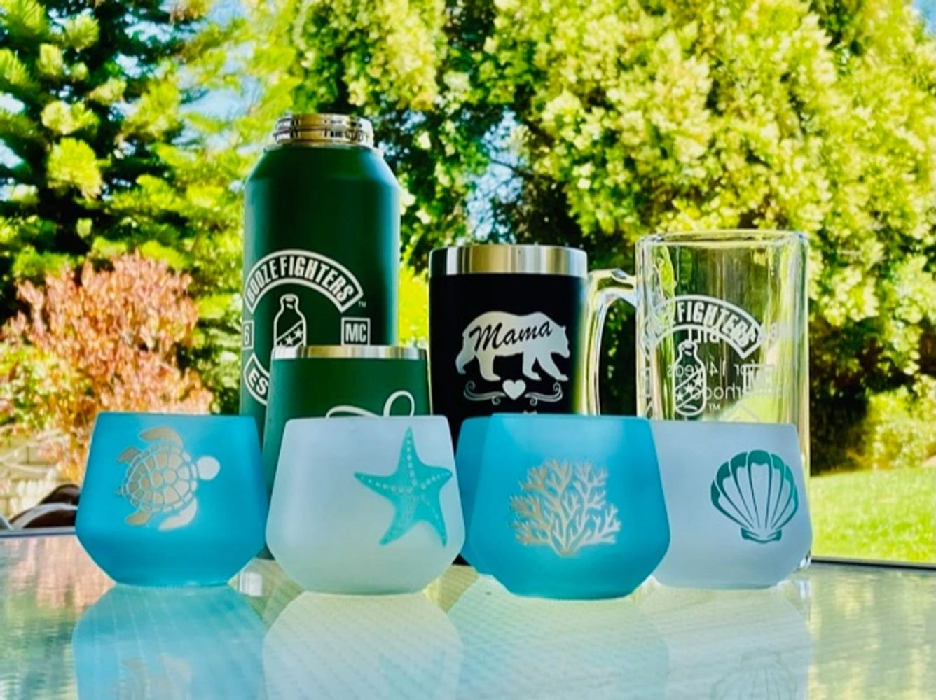 a picture of some tumblers, water bottles and engraved beach themed candle holders on a glass table