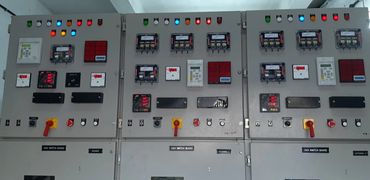 Three electrical control panels with switches, meters, and indicator lights.