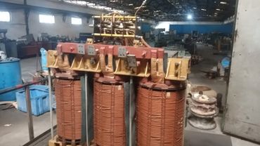 Large industrial transformer coils inside a factory.