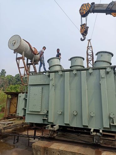 Two men working on a large industrial transformer outdoors.