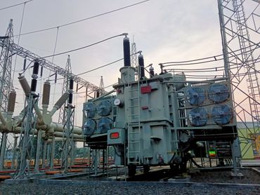 High-voltage electrical transformer with cooling fans at a power substation.