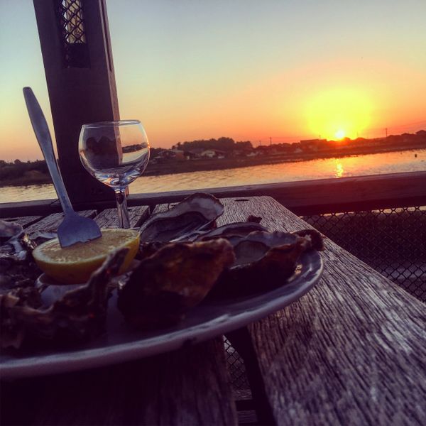 A plate of oysters on a picnic bench with a sunset in the background