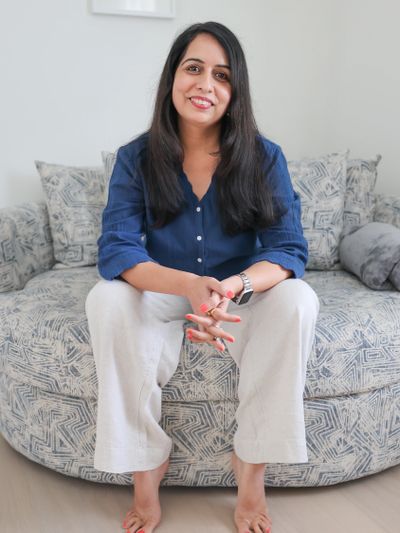 Woman sitting comfortably on a patterned sofa, smiling warmly.