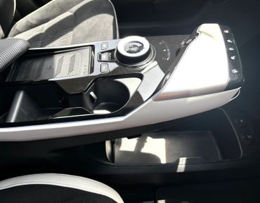 Modern car center console with controls and cup holders.