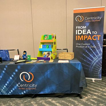 Tradeshow setup with table, tablecloth, samples, and banner beside the table.