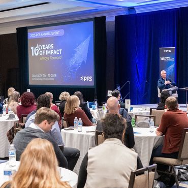 Image of company event attendees and presentation screen in the background.