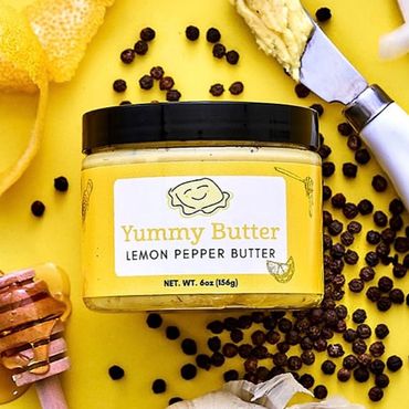 Yummy Butter Lemon Pepper Butter jar with label. Ingredients and butter knife surround the jar.