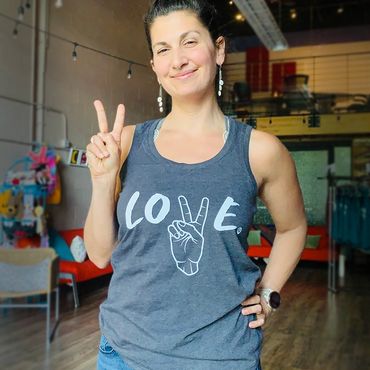 Women modeling grey tank top with the word love and peace symbol.