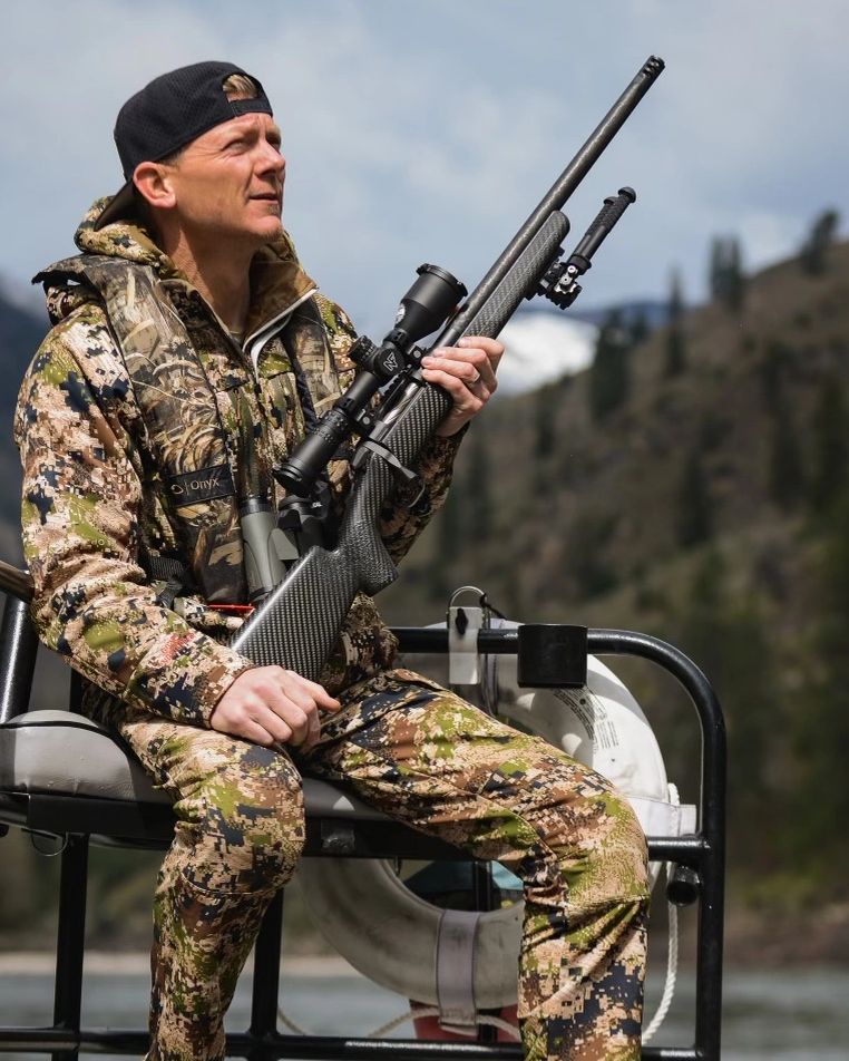 Bear Hunter on a jet boat going up river with carbon fiber bolt action rifle and night force scope.