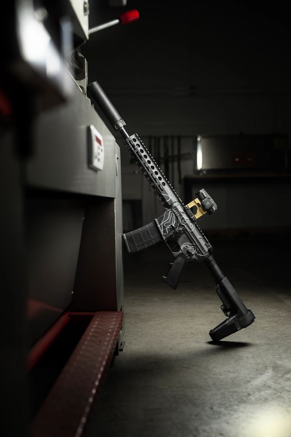 AR-15 with graphite black and storm topographic cerakote. Surefire RC2 and Unity Riser with red dot