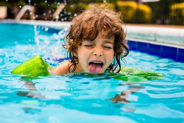 toddler swimming and licking water