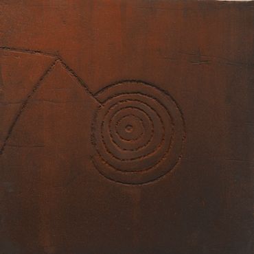 Rust-colored surface with a spiral and triangular carved design.