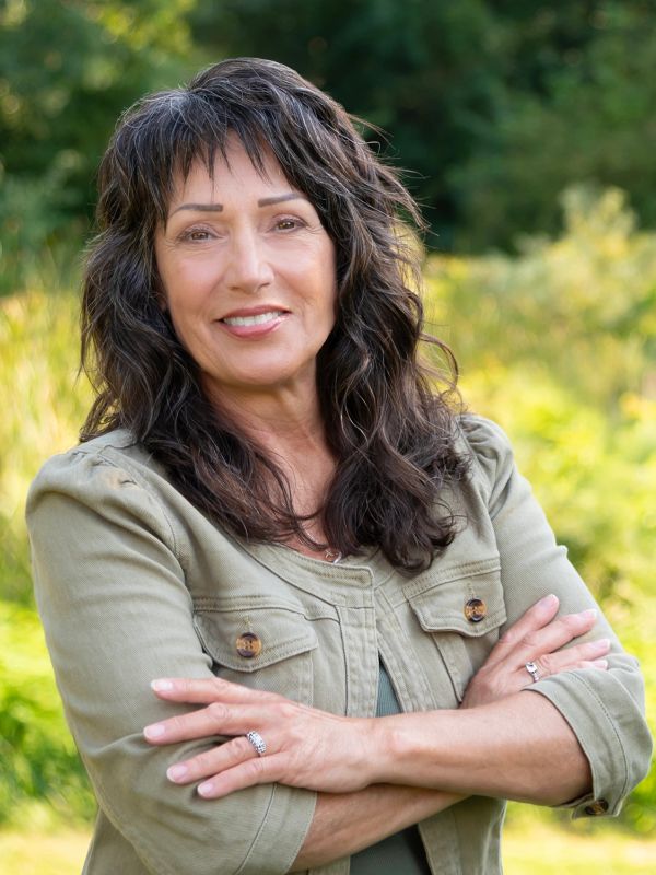 Smiling woman with curly hair outdoors.