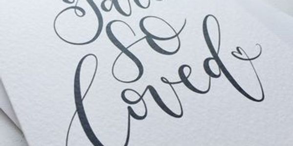 Elegant calligraphy of 'So Loved' on paper.