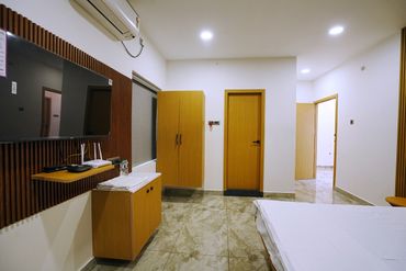Modern bedroom with wooden cabinets, tiled floor, and wall-mounted TV.
