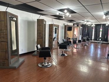 Modern hair salon with multiple styling stations and wooden floors.