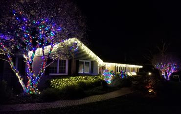 House decorated with colorful and white Christmas lights at night.