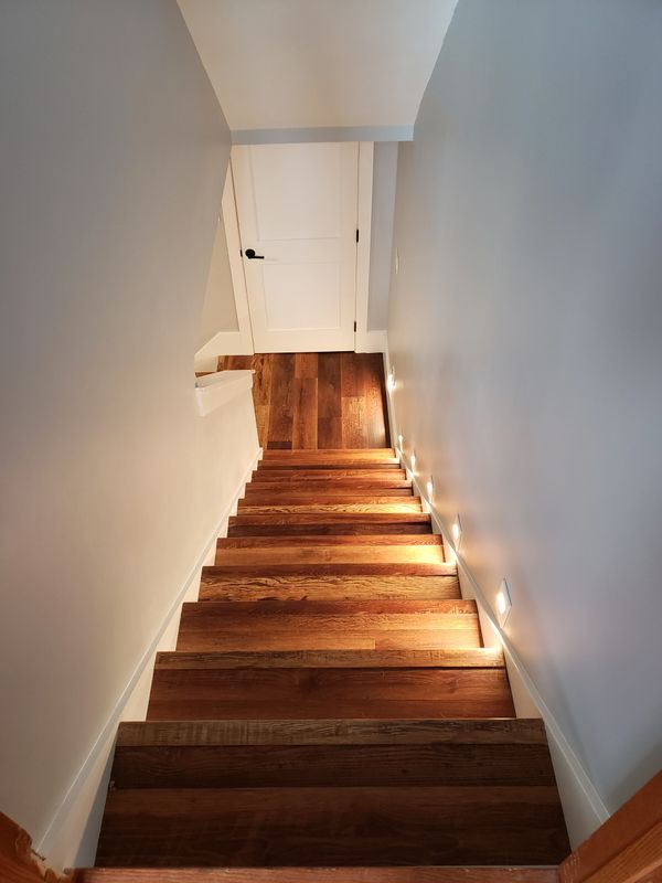 Basement Remodel Progress Picture, Stair Case Complete, Lighting, and Landing Storage Closet.