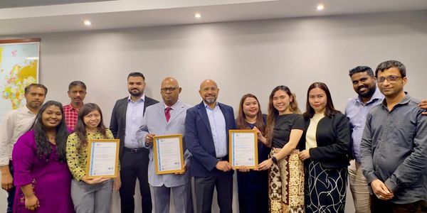 Group photo of diverse professionals holding framed certificates indoors.