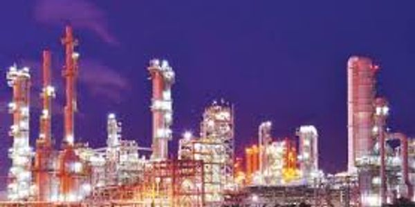 Industrial refinery complex illuminated at night under a dark sky.