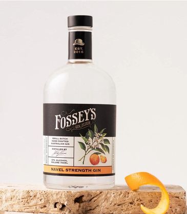 A bottle of Fossey's Navel Strength Gin with orange peel on stone.