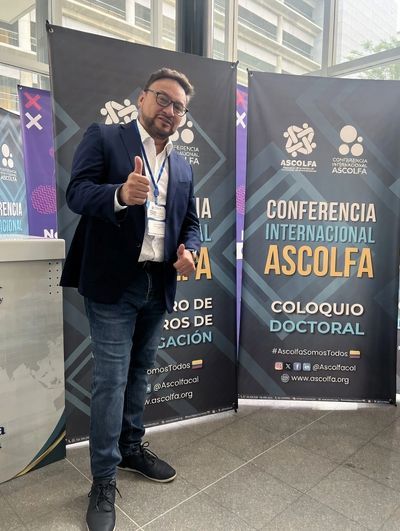 Man in business attire giving thumbs up at ASCOLFA conference.