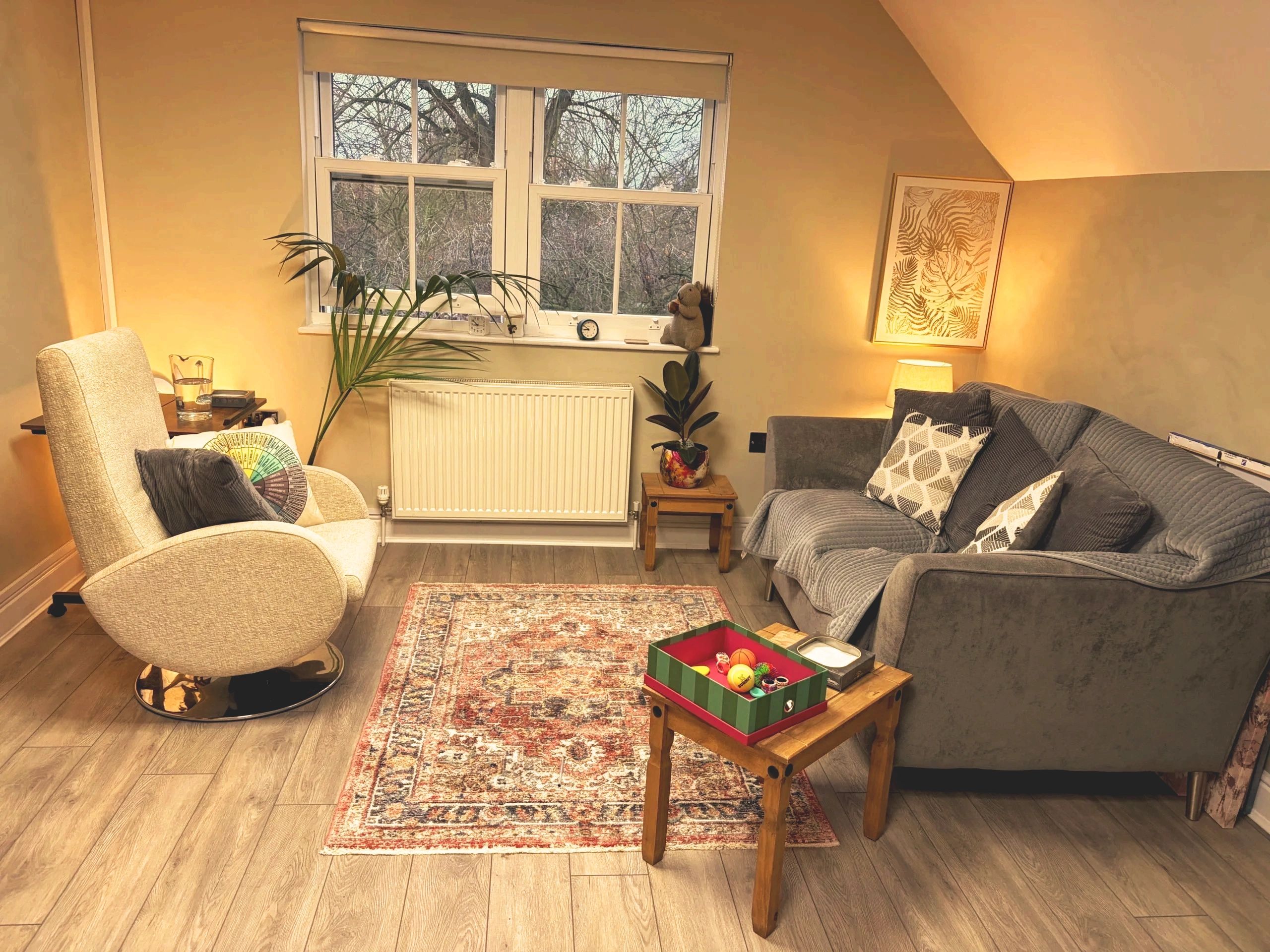 Cozy living room with armchair, sofa, plants, and warm lighting.