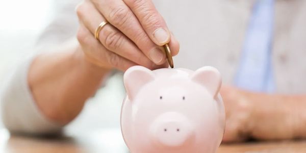 Woman placing coin into a pink piggy bank